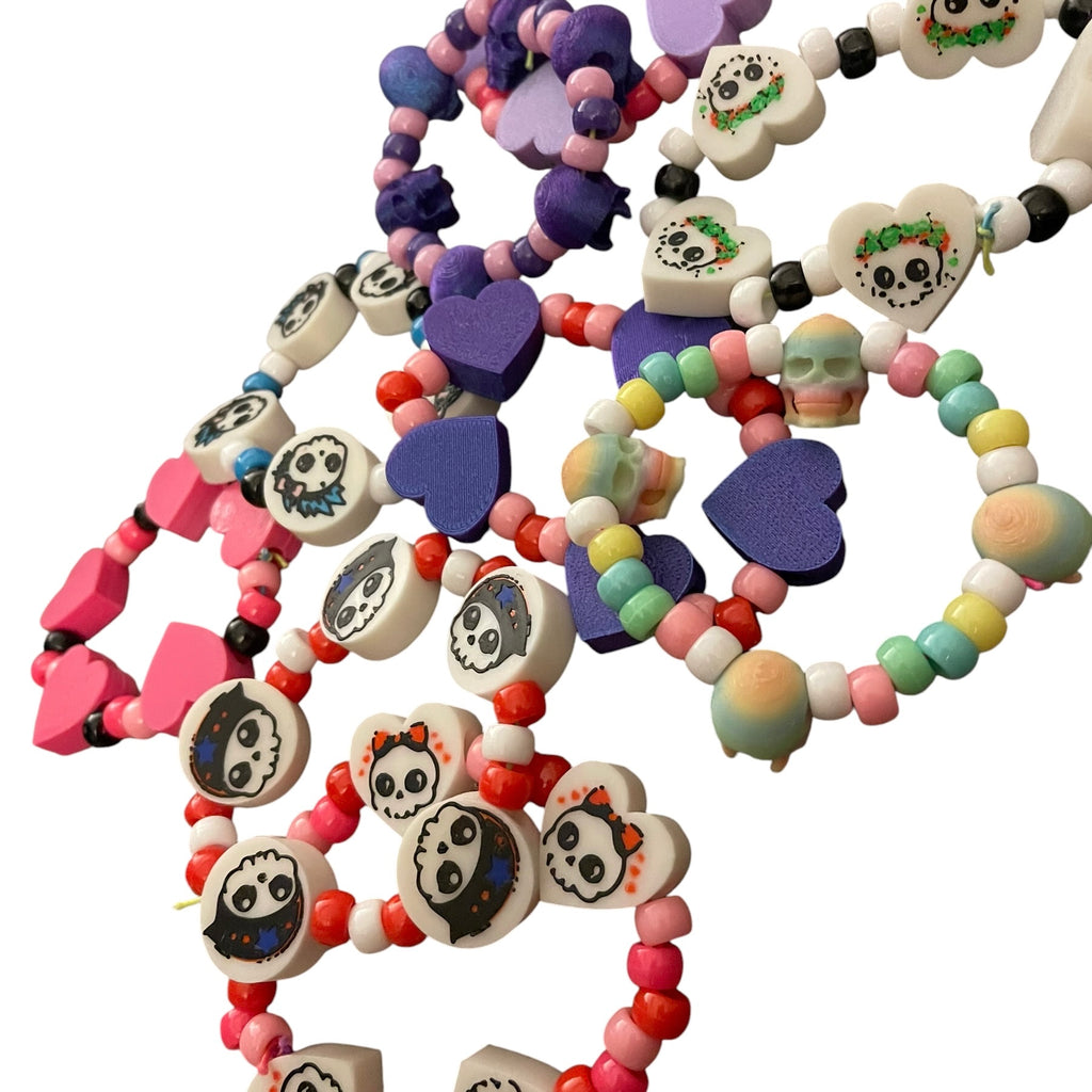 A collection of colorful beaded bracelets with skull and heart charms, displayed on a clean white background.