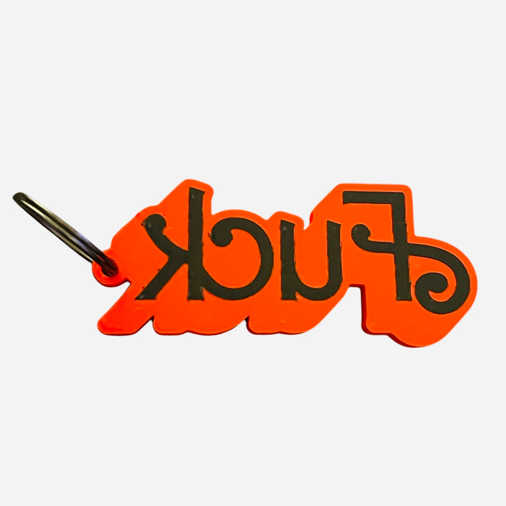 A red and black novelty keychain, featuring the word 'fuck' in black stylized lettering on a red background, with a metal keyring on a white background.