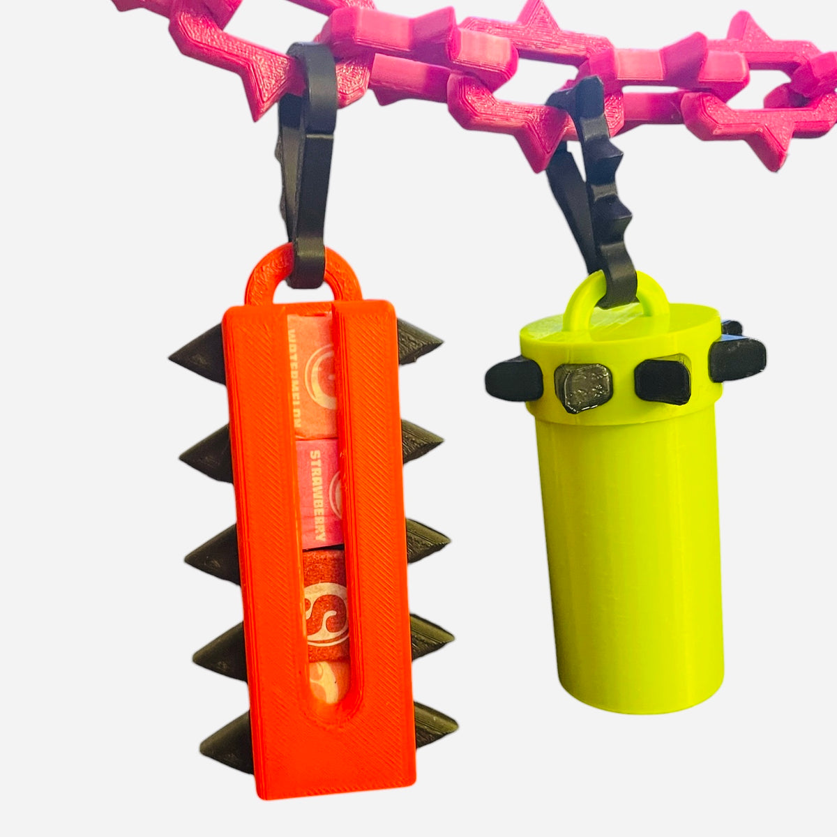 A red candy holder with black spikes, hanging from a hot pink chain, on a white background.