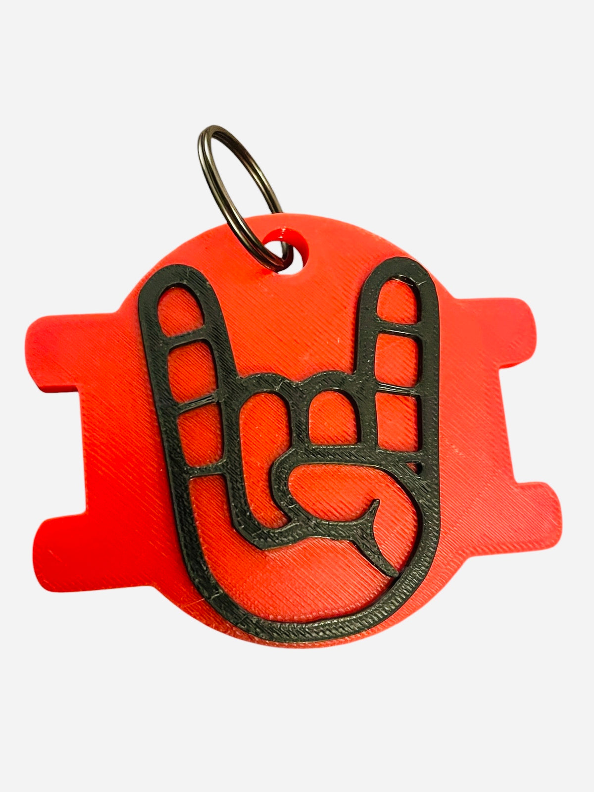 A red 3D-printed bag chain with a black metal keyring, featuring a black cutout design of a hand making the rock on. The tag is shown against a plain white background.
