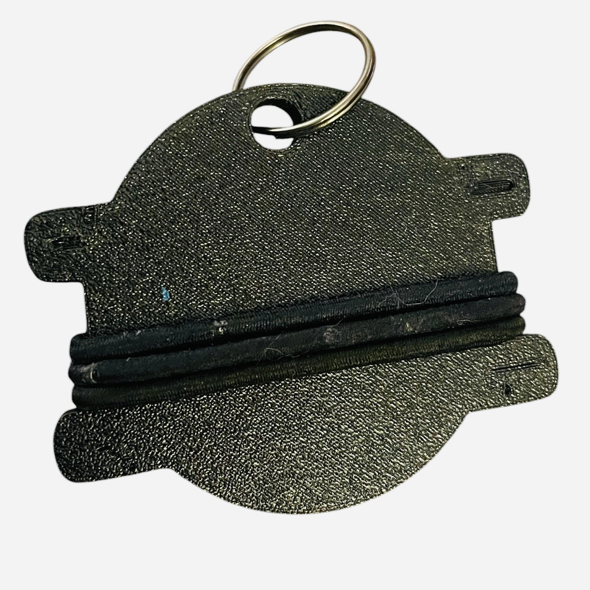 A textured black keychain tag with a metal split ring, featuring a horizontal black elastic band across the center, shown on a plain white background.
