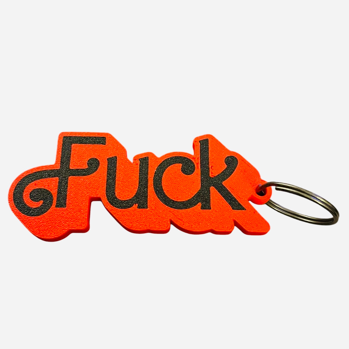 A red and black 3d printed keychain featuring the word 'Fuck' in black lettering in a Barbie font, attached to a silver metal split ring, set against a plain white background.
