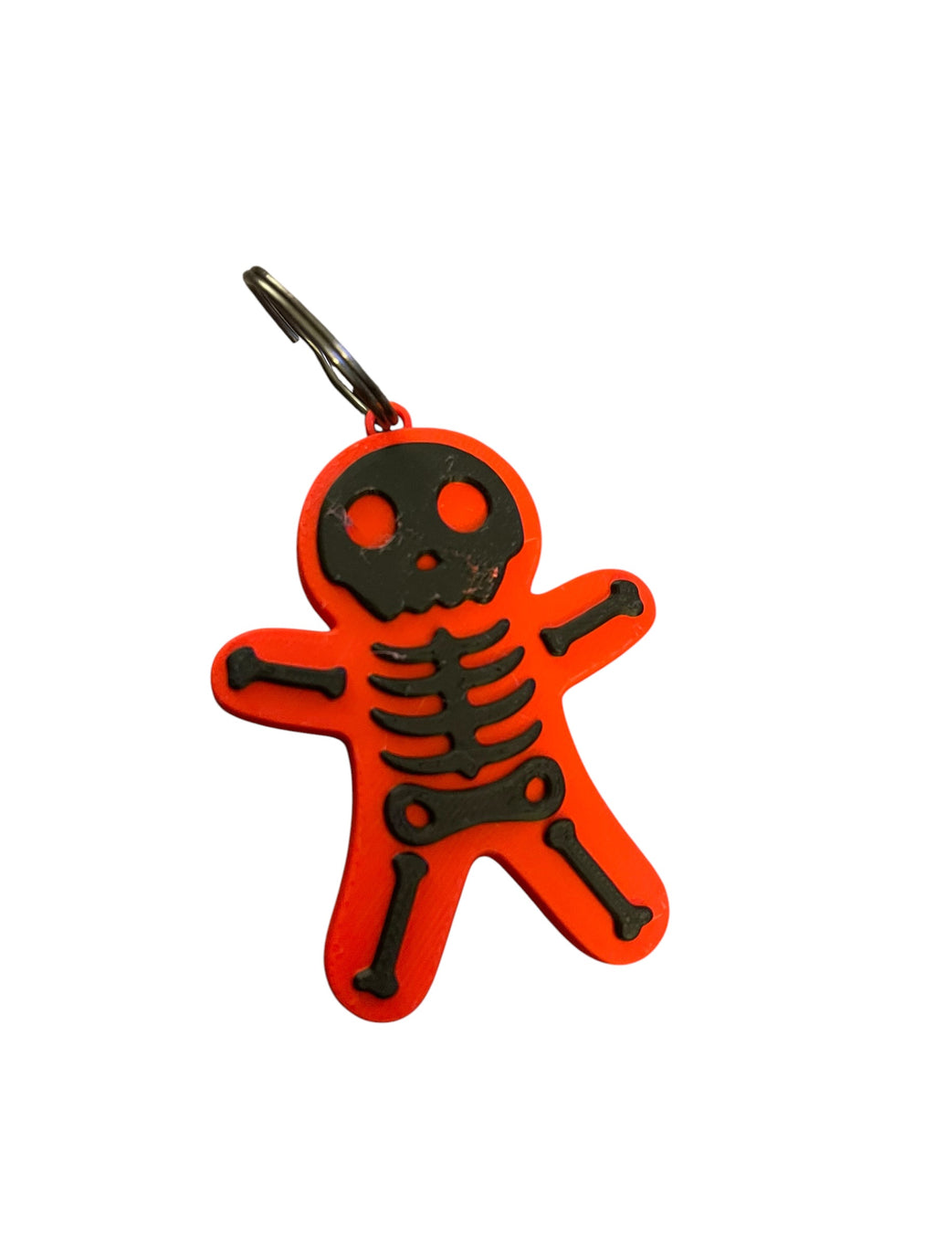 A red and black skeleton-shaped keychain or bag charm with a metal key ring, shown on a plain white background.