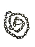 A coiled black 3d printed chain with spikey links, shown on a plain white background.