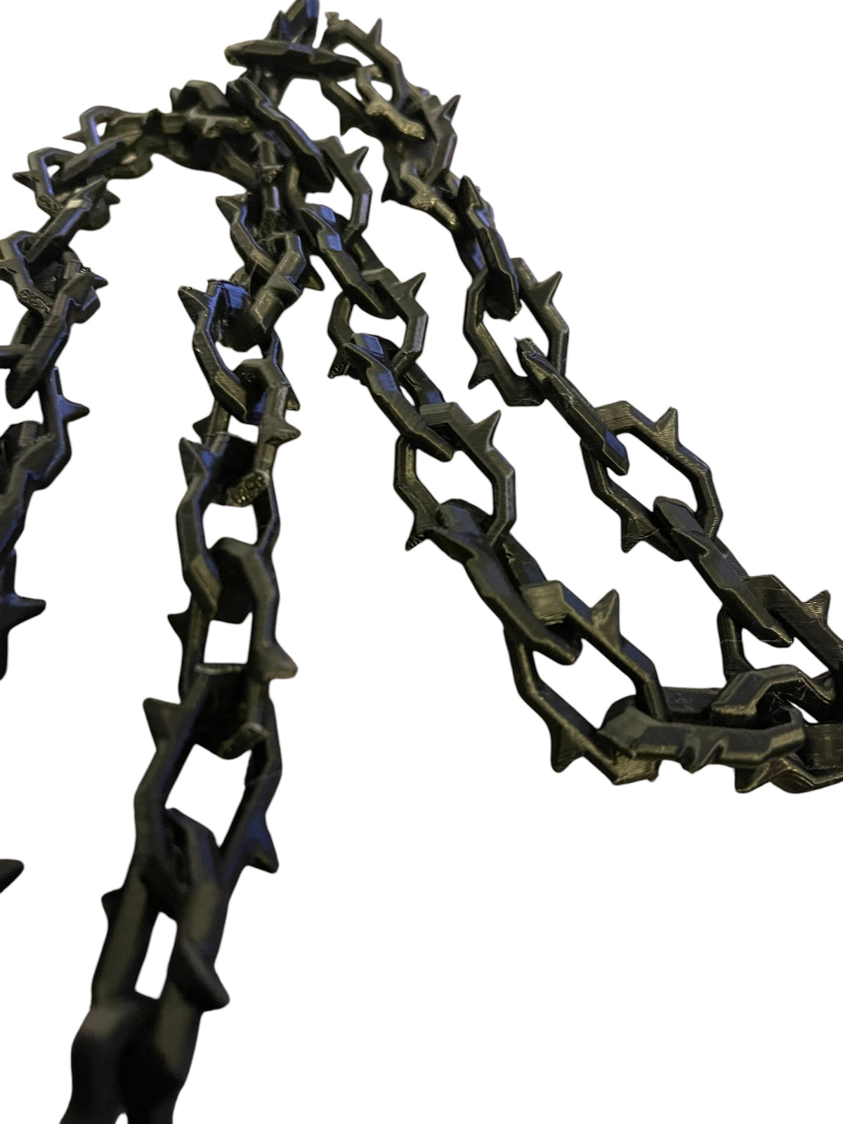 A close-up of a black 3d printed chain with spikey links, shown against a plain white background.