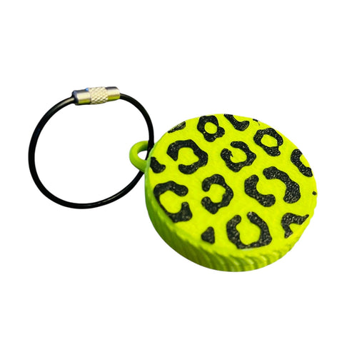 An electric green screw top container keychain with leopard print on a white background, designed to hold an AirTag. Features a wire keychain connector.