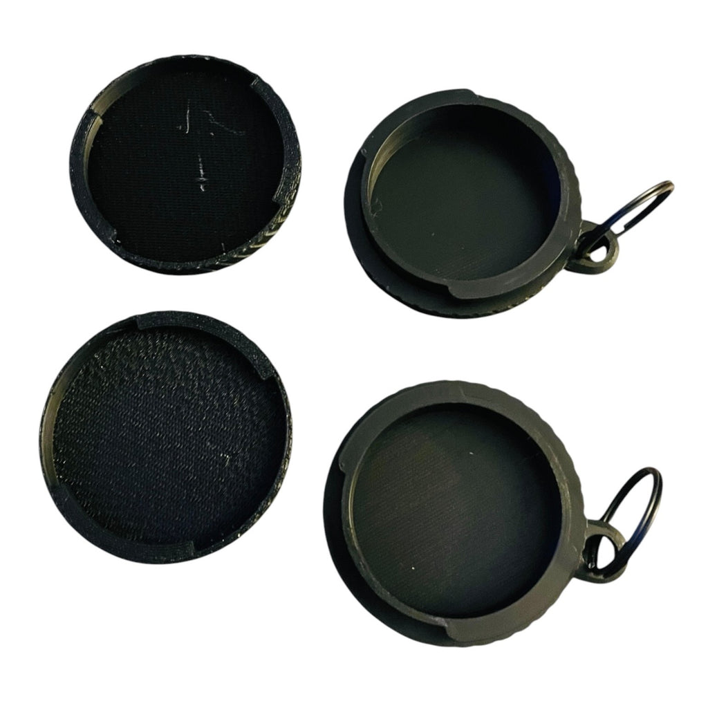 The interior view of two round black screw top container keychains on a white background. Both feature a black split ring.